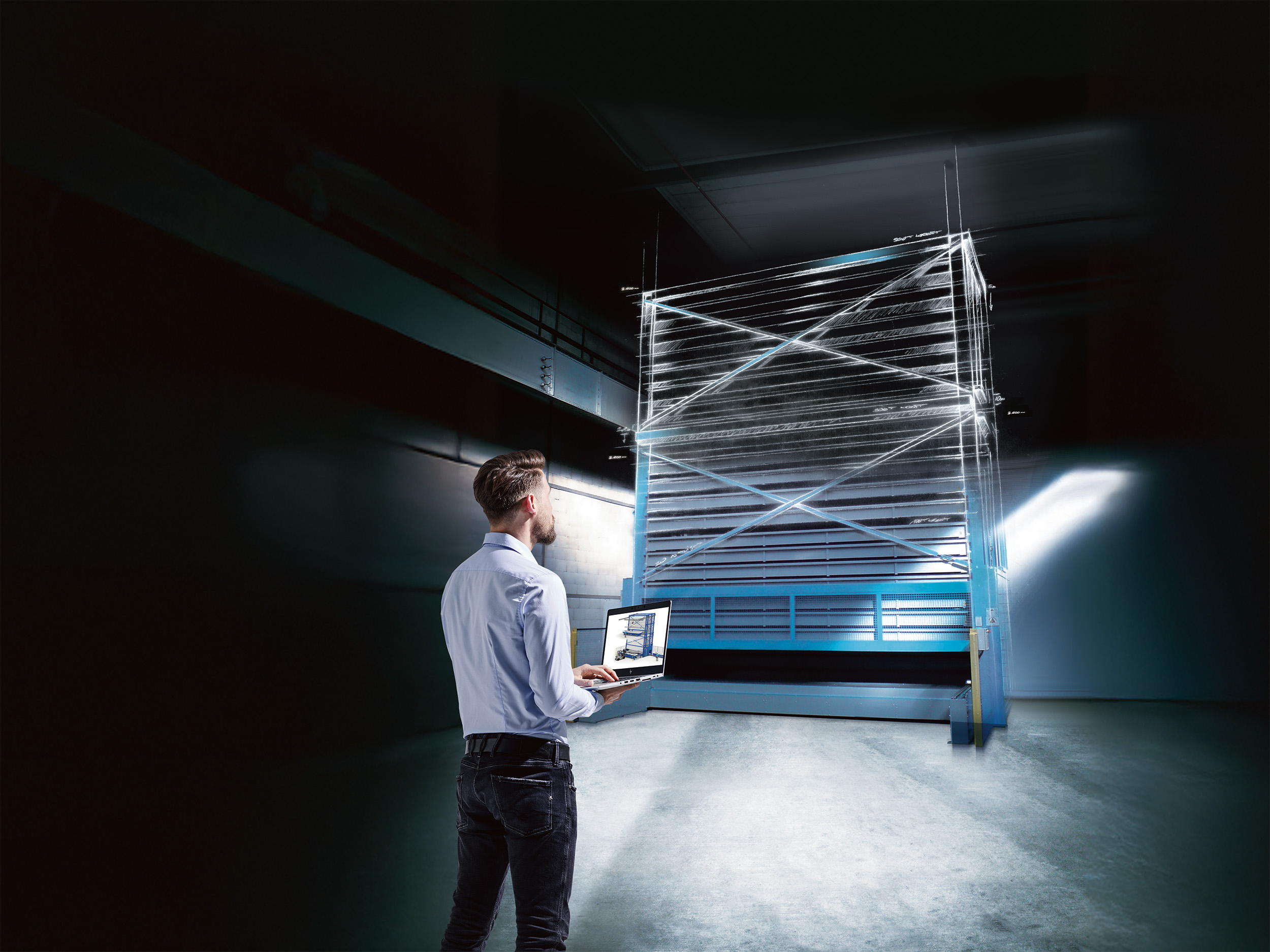 Mann steht mit Laptop vor einem automatisierten Turmlager in Planung